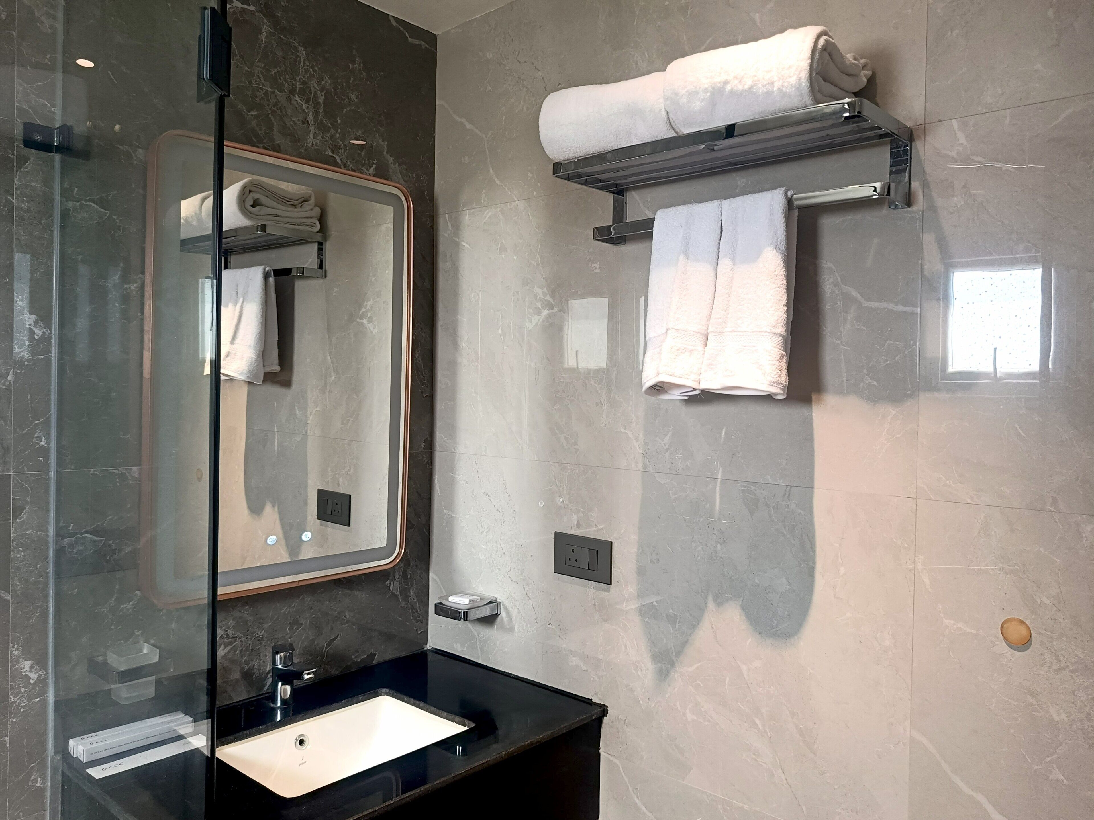Ein modernes Badezimmer mit einem in Glas eingefassten Waschbecken, einem Spiegel und Handtuchhaltern.