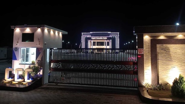 A gated entrance with a modern building in the background, a small structure with a sign indicating an exit, and a decorative fence. - Crystal Residency (Tiruchirappalli)