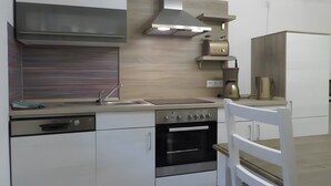 Eine moderne Küche mit Einbauofen, Edelstahl-Dunstabzugshaube und Kaffeemaschine.