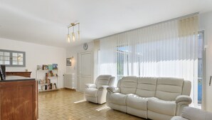 A living room with a sofa, armchairs, a wooden cabinet, and a bookshelf. - Apartment 'Maison Grenoblois' with Balcony (Eybens)