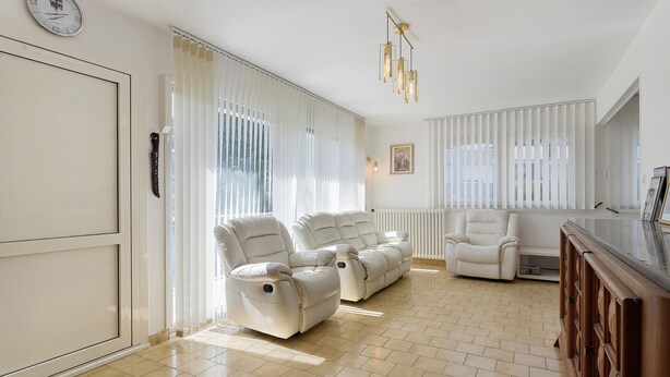 A spacious living room with two reclining sofas, a white radiator, and a wooden cabinet. - Apartment 'Maison Grenoblois' with Balcony (Eybens)