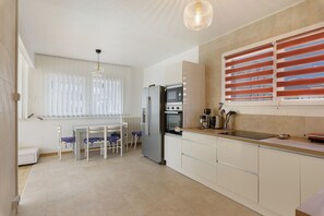Une cuisine moderne équipée d’un réfrigérateur, d’un four à micro-ondes et d’une cuisinière. Un coin repas avec une table et des chaises est également disponible.