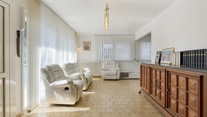 A spacious living area with a sofa set, a chair, a wooden cabinet, and a radiator. - Apartment 'Maison Grenoblois' with Balcony (Eybens)