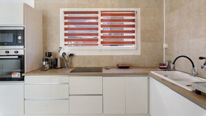 A kitchen with a built-in oven, a coffee maker, a kettle, and a sink. - Apartment 'Maison Grenoblois' with Balcony (Eybens)