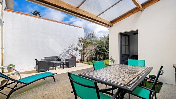 Un patio al aire libre con una mesa y sillas, una tumbona y un área cubierta con vista al cielo.