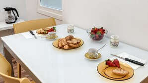 A dining table with plates of food, a coffee maker, and a bowl of strawberries. - Modern and cozy apartment, freshly renewed!. It features 2 fully equipped bathrooms with shower, WC, and bidet. The kitchen is brand new and fully equipped with an oven and microwave. The property includes 4 air conditioning and heating units, one in eac (Firenze)