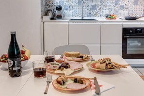 A dining table with plates of food, a bottle, and glasses. - Cozy apartment located just outside the historic center of Florence, ideal for up to 3 guests. It features a bedroom with a double bed and a comfortable single sofa bed. The living area is bright and includes a fully equipped kitchen, perfect for any nee (Firenze)