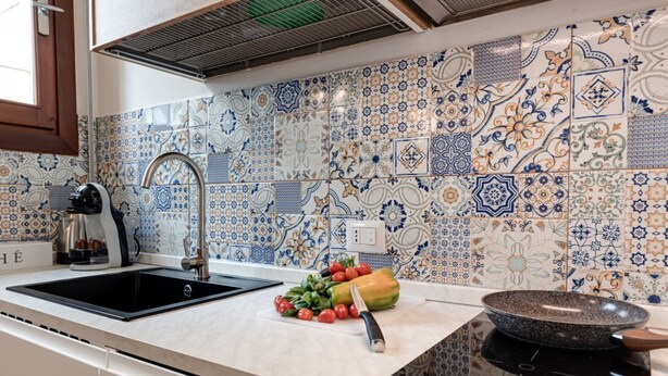 Una cocina con un lavabo, estufa y encimera con verduras.