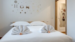 Habitación de hotel con cama, almohadas, pared decorada con letras y espejo con diseño floral.