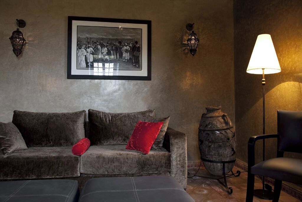 A room with a sofa, a chair, a lamp, and a framed photograph on the wall.