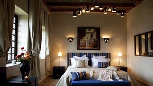 A hotel room with a large bed, bedside lamps, a painting on the wall, and a vase with flowers on a nightstand. - kasbah illy (Tifni)