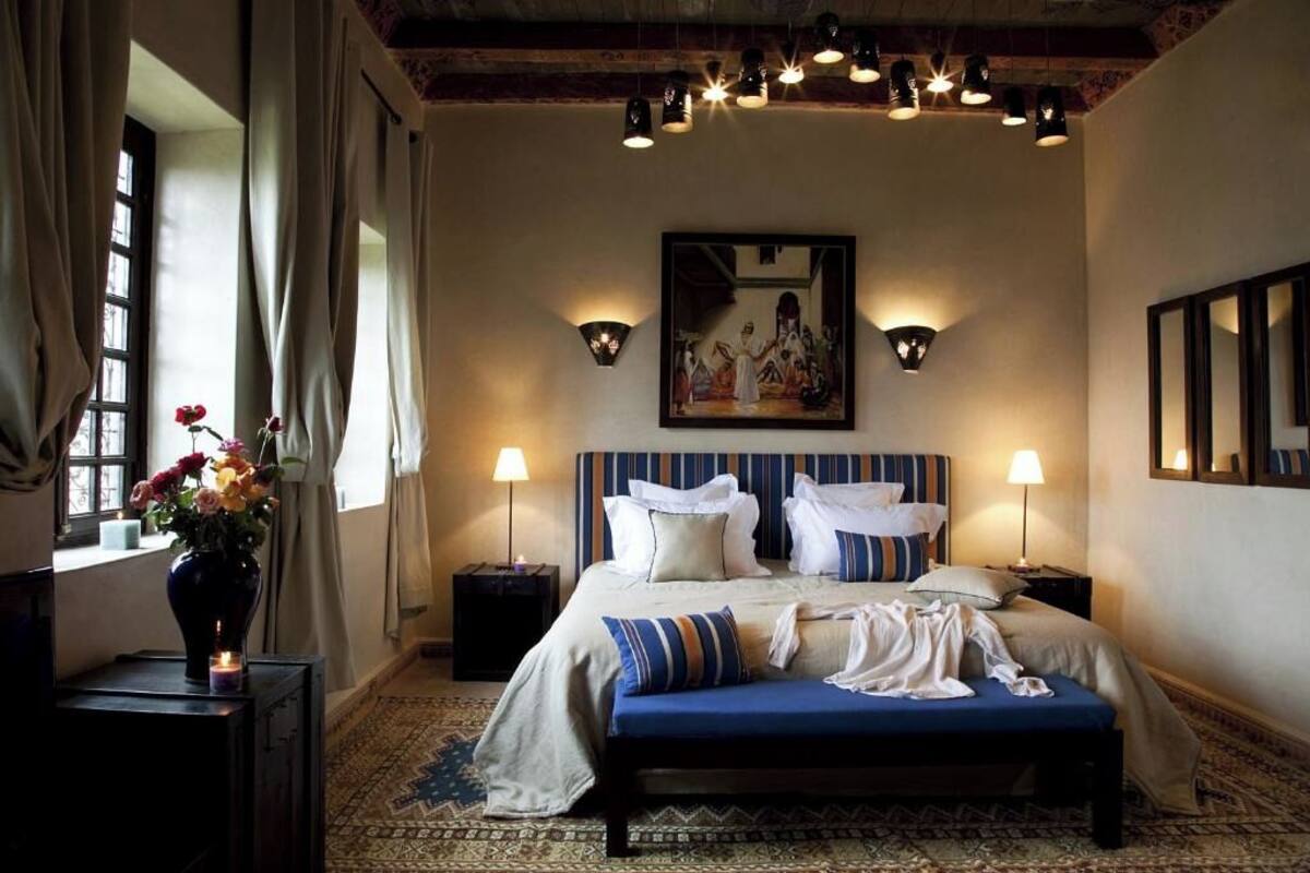 A hotel room with a large bed, bedside lamps, a painting on the wall, and a window with curtains.
