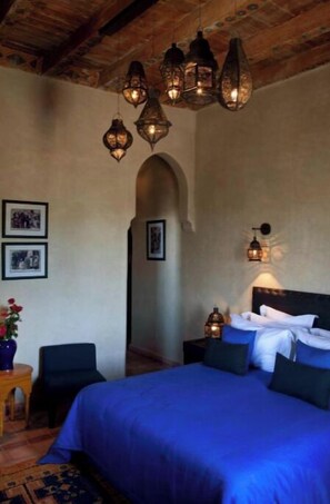 A bedroom with a large bed, a wooden ceiling, and wall-mounted lights.