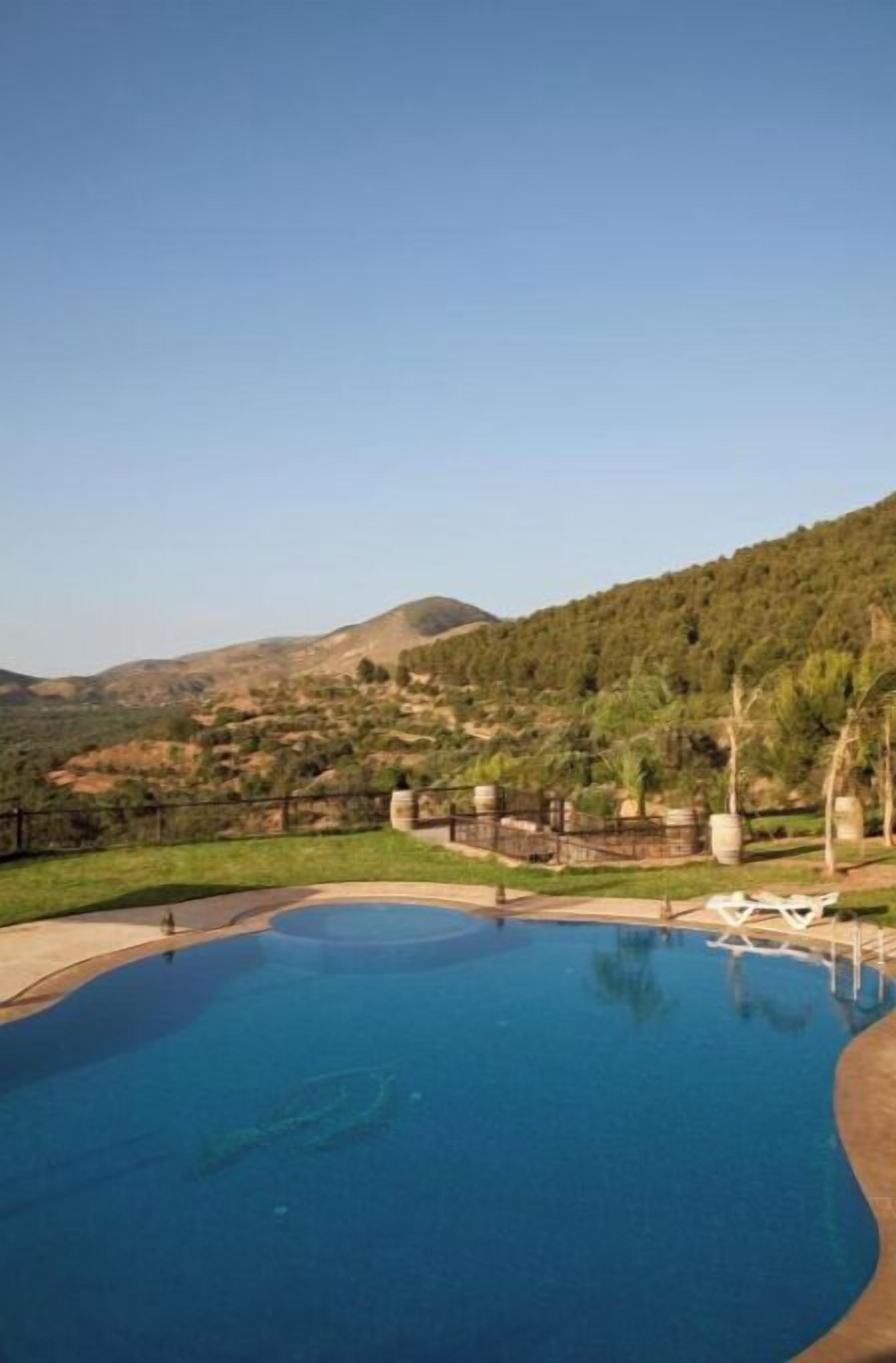 A swimming pool with a view of a hilly landscape.