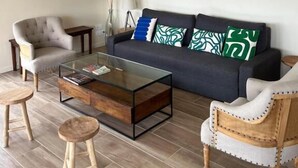 Un salon comprenant un canapé, deux fauteuils, une table basse et des œuvres d’art accrochées aux murs.