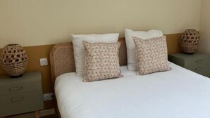Une chambre à coucher avec un grand lit, deux tables de chevet et un panier en osier de chaque côté.
