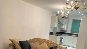 A living room with a sofa, a colorful rug, and a kitchen in the background. - House- Sleeps 6 & Free Parking (Grays)