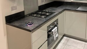 A modern kitchen with a gas stove, oven, and white cabinetry. - House- Sleeps 6 & Free Parking (Grays)