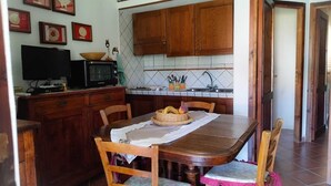 Une cuisine avec des meubles de rangement en bois, un four à micro-ondes, une table à manger avec des chaises et un dosseret carrelé.