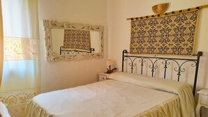Un lit bien fait, recouvert d’une couvre-lit blanche et agrémenté d’une tête de lit décorative.