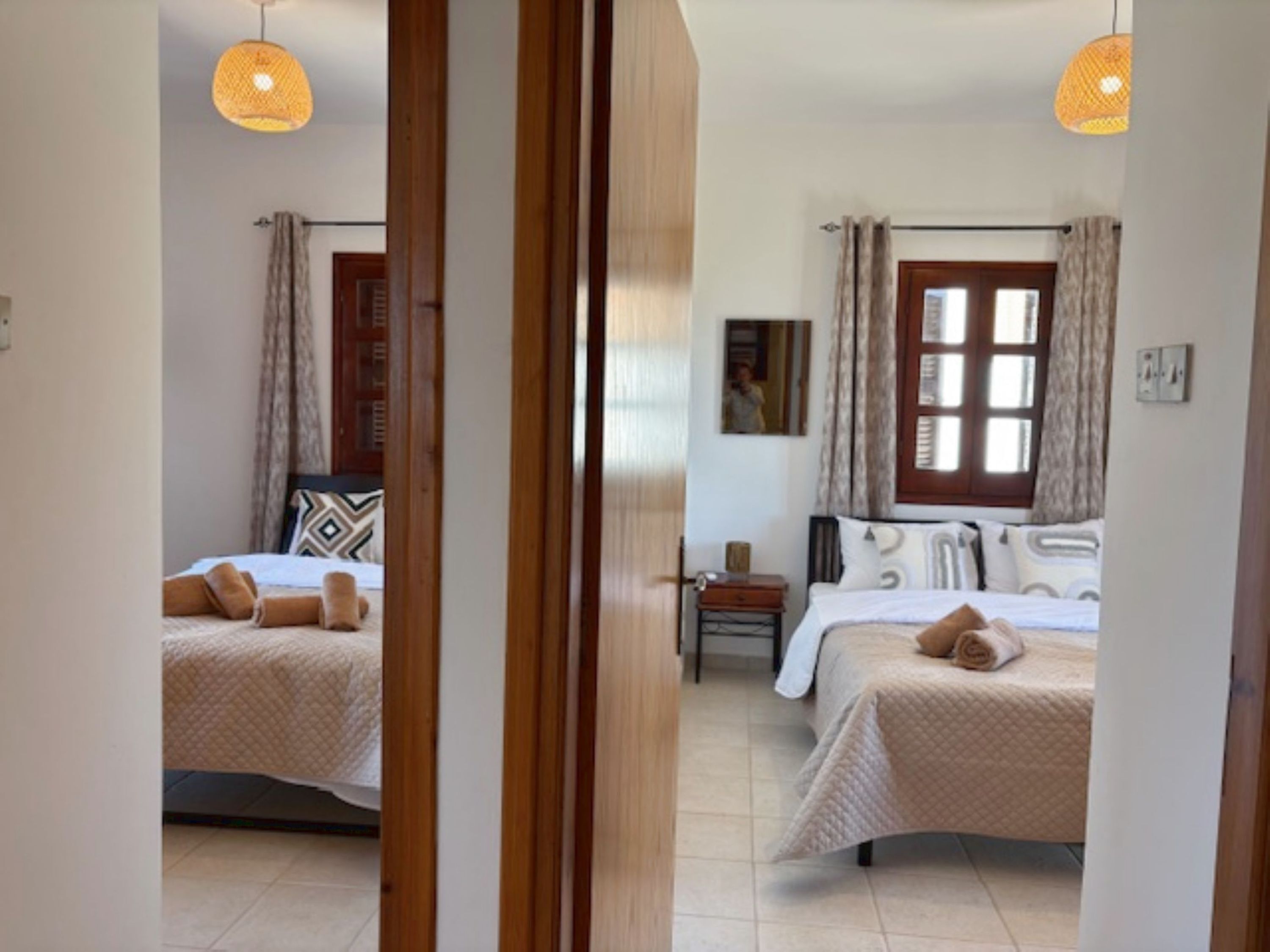 A bedroom with two beds, a window, and a nightstand.