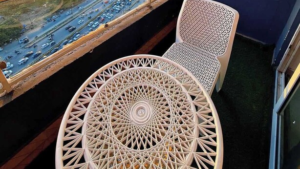 A balcony with a view of a cityscape, a round table, and two chairs. - Sunshine Stays, Gaur City Centre, Gr Noida West (Greater Noida)
