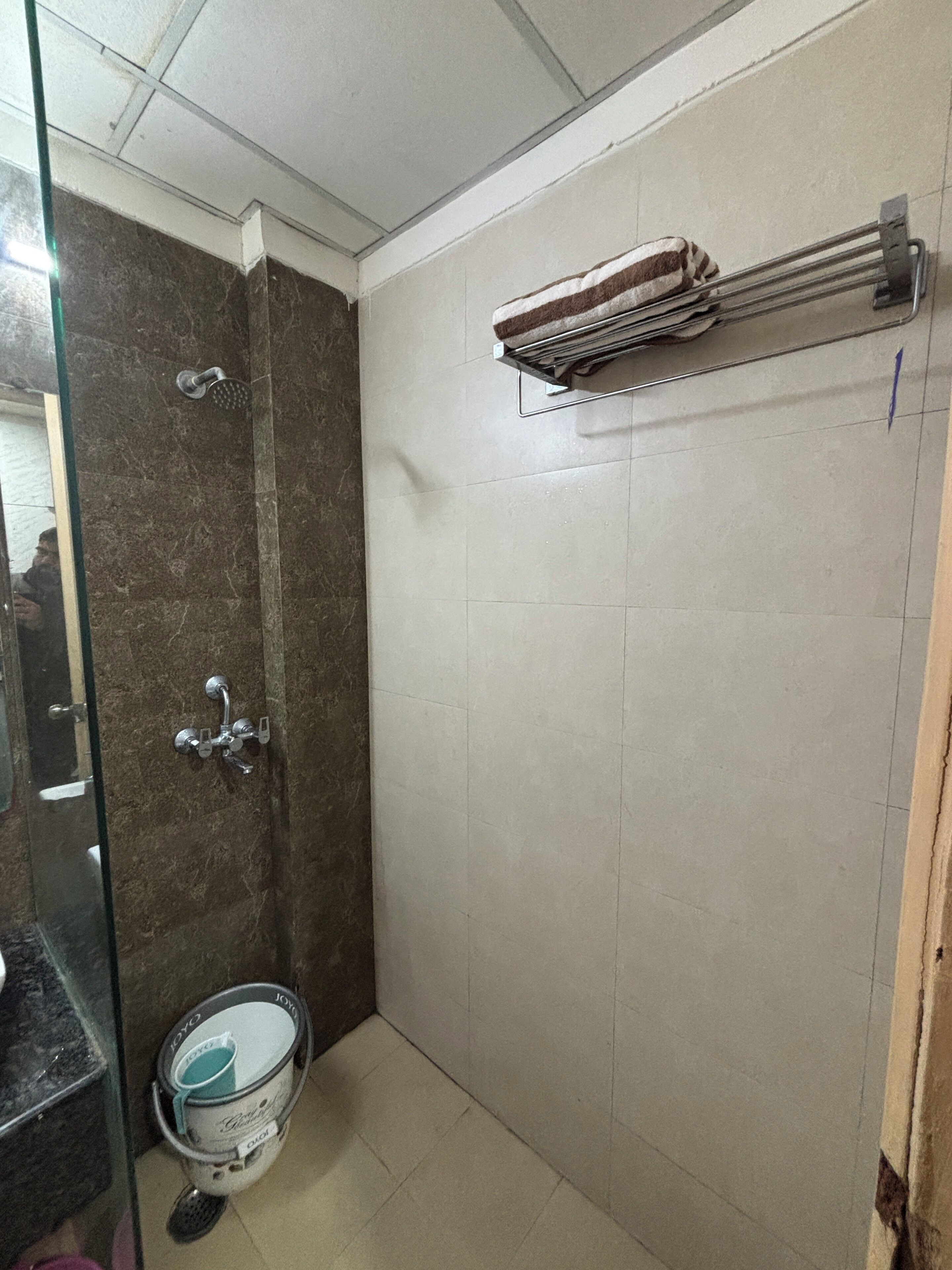 A bathroom with a shower, a towel rack, and a toilet.
