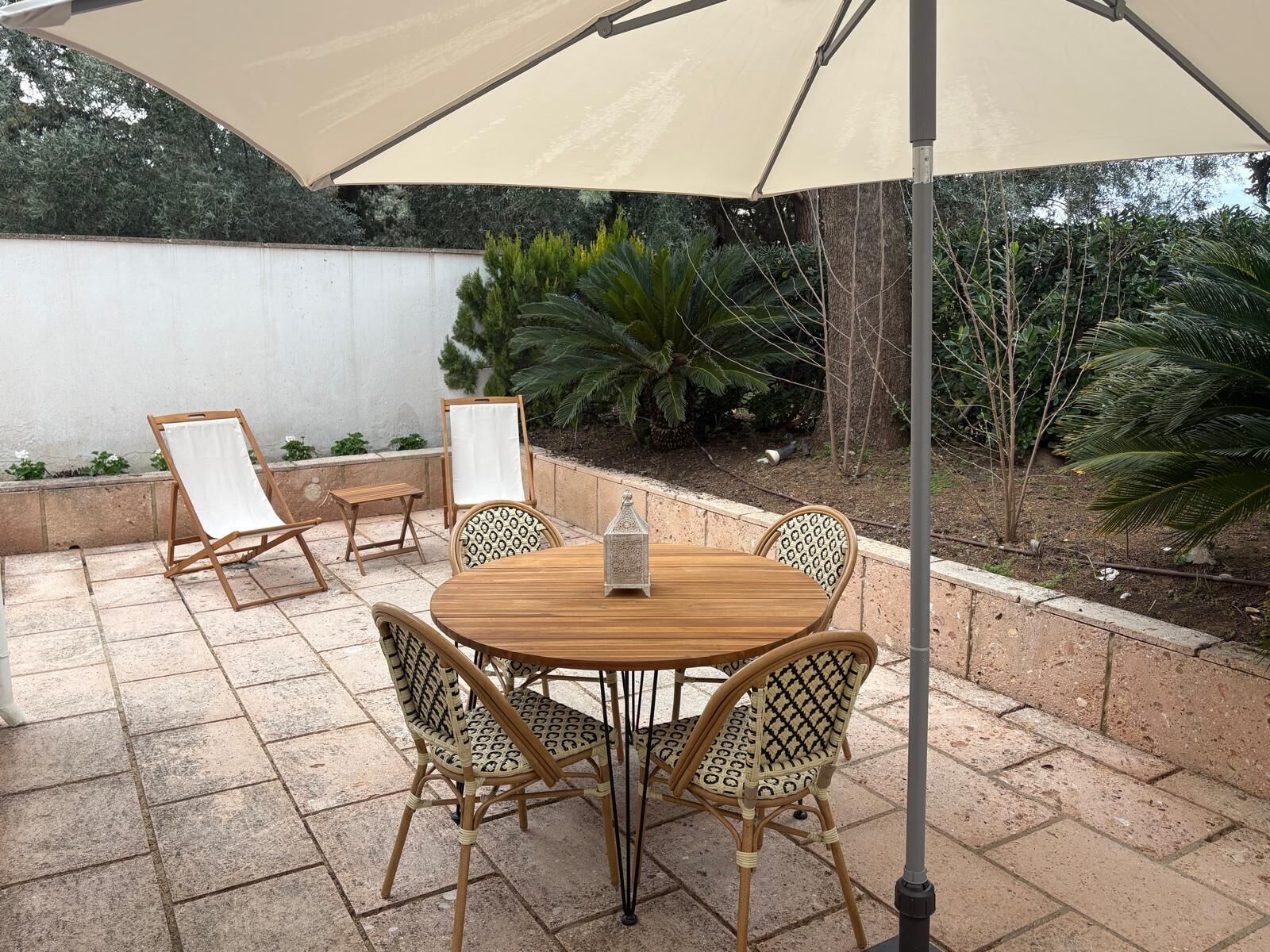 A patio with a round table, four chairs, and a large umbrella.
