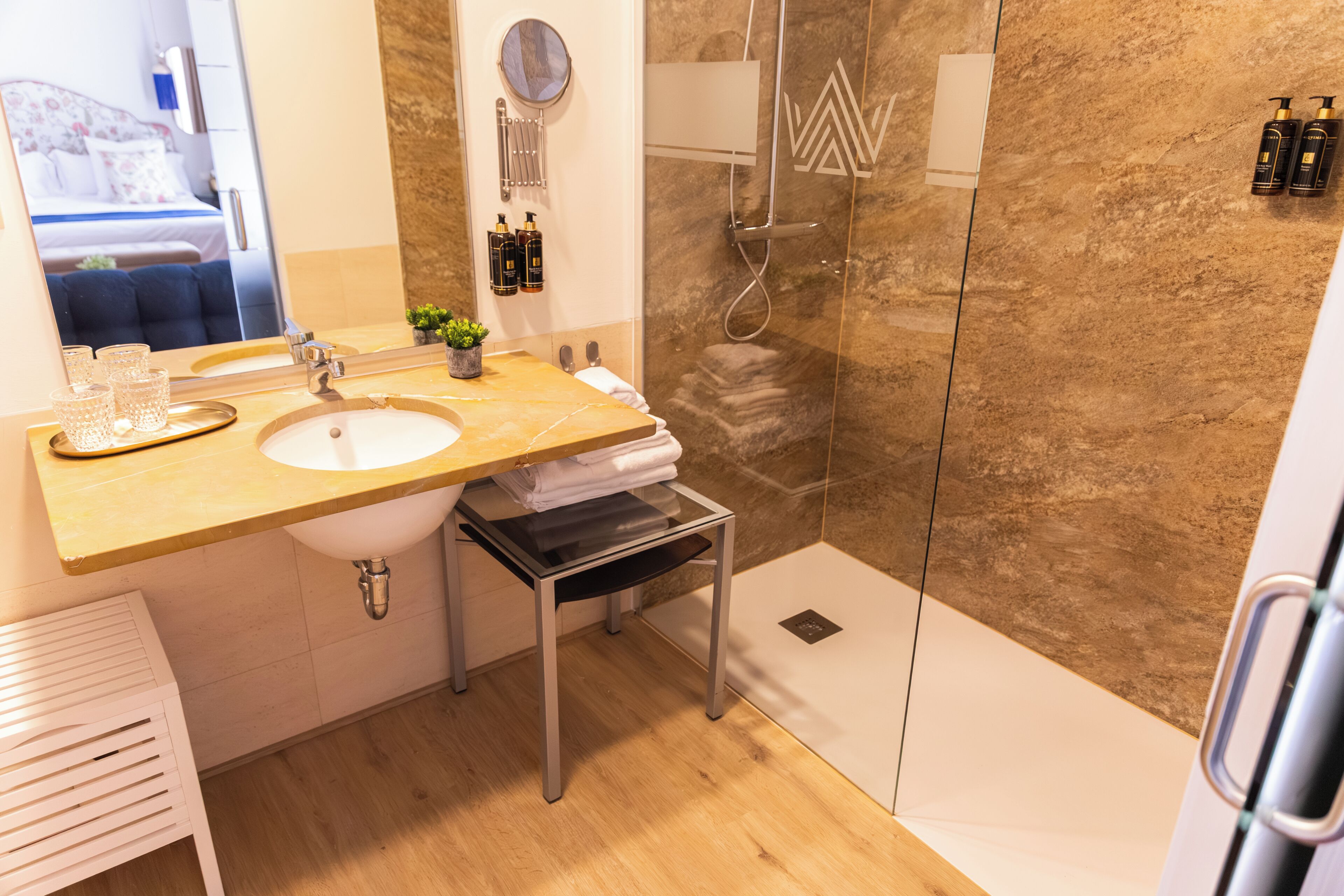 Un baño moderno con lavamanos, espejo y ducha.