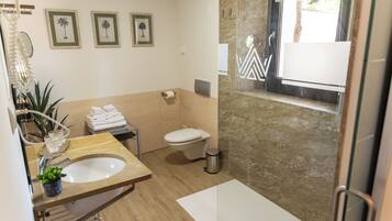A modern bathroom with a marble sink, toilet, and a small window with a view.