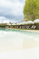 Una piscina al aire libre, sombrillas, sillones reclinables de piscina