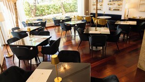 A restaurant with multiple tables and chairs, a stone wall, and a view of greenery outside. - Hotel Boutique Palacio del Moral (Ronda)