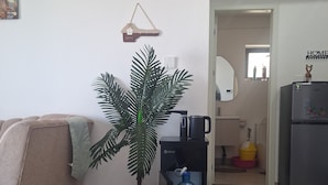 Una sala de estar con sofá, dispensador de agua, cafetera y refrigerador.