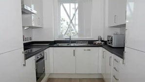 Una cocina moderna con armarios blancos, una encimera negra, un microondas y un ventanal.