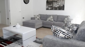 Una sala de estar moderna con un sofá seccional gris, una mesa de centro blanca y un cojín decorativo blanco y negro.