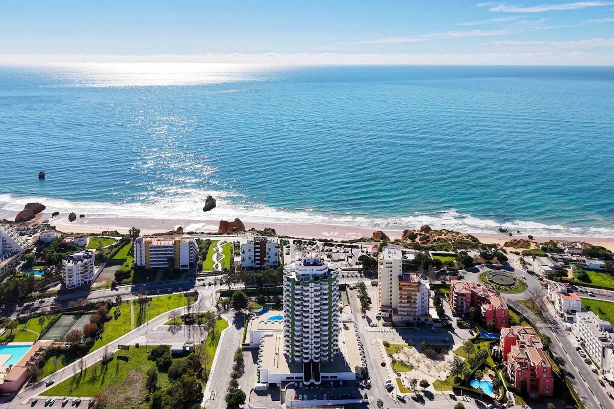 Vista aérea de una zona hotelera costera con un edificio grande, una playa y una vista despejada del océano.