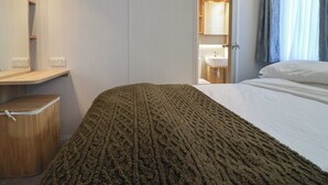 A hotel room with a bed, a bedside table, a mirror, a bathroom with a sink, and a window with curtains. - Lodge 22, Moselle (Malton)