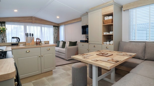 A compact kitchen with a dining area, a sofa, and a TV mounted on the wall. - Lodge 22, Moselle (Malton)