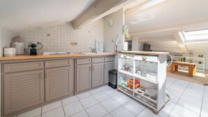 Et køkken med flisebeklædt bagvæg, træskabe, en bordplade og en lille hylde.