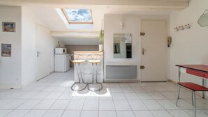 Et rummeligt køkken med ovenlys, et køleskab og en bar med barstole.