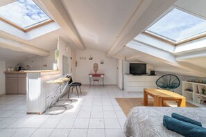Eine kompakte, moderne Wohnung mit Dachfenstern, einer Küchenzeile, einem Essbereich und einem Wohnraum.