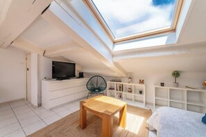 Eine moderne Wohnung mit Oberlicht, einem Holztisch, einem Fernseher und weißen Regalen.