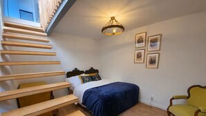 A bedroom with a bed, a chair, a staircase, and a chandelier. - Jakby Poza Miastem (Kraków)