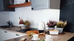 A modern kitchen with a wooden countertop, a kettle, a loaf of bread, and potted plants. - Jakby Poza Miastem (Kraków)
