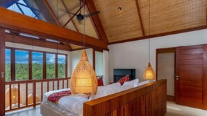 A bedroom with a large bed, wooden headboard, and a balcony with a view of greenery. - Tempat Santai Bali (Ubud)