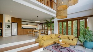 A modern living room with a sofa, coffee table, and a staircase leading to an upper level. - Tempat Santai Bali (Ubud)