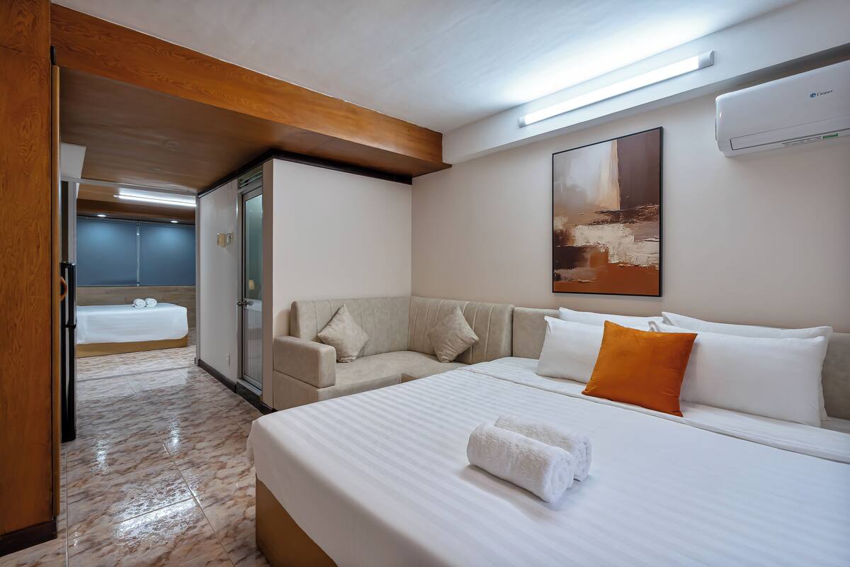 Een hotelkamer met een bed, een slaapbank, een inloopkast en een badkamer met een bad.