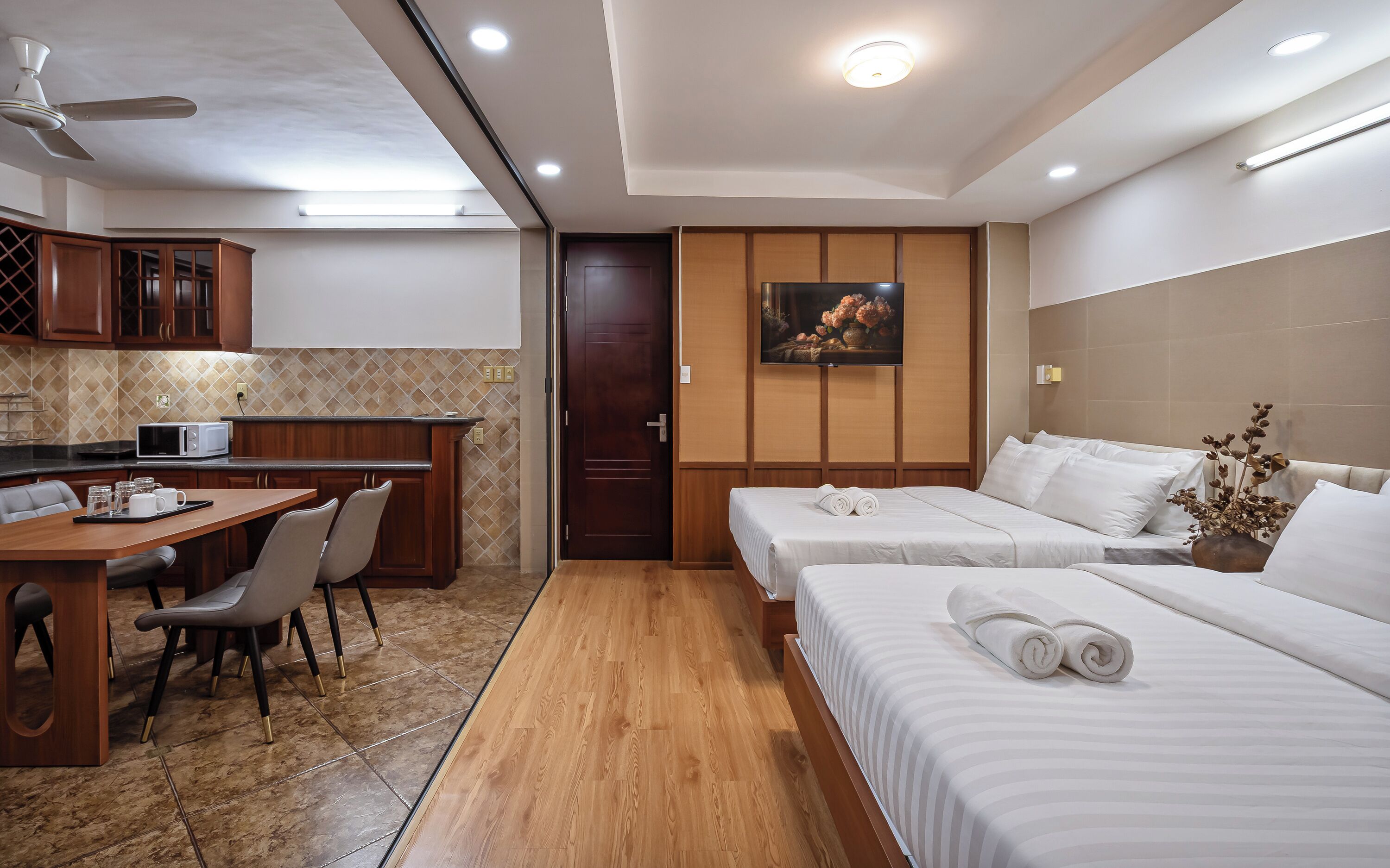 A hotel room with a kitchenette, a dining area, and two beds.