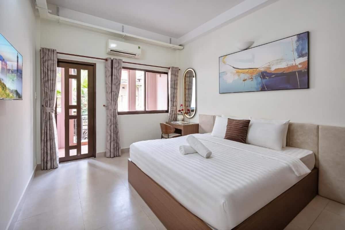 Een hotelkamer met een bed, een bureau, een stoel, een spiegel en een schilderij aan de muur.