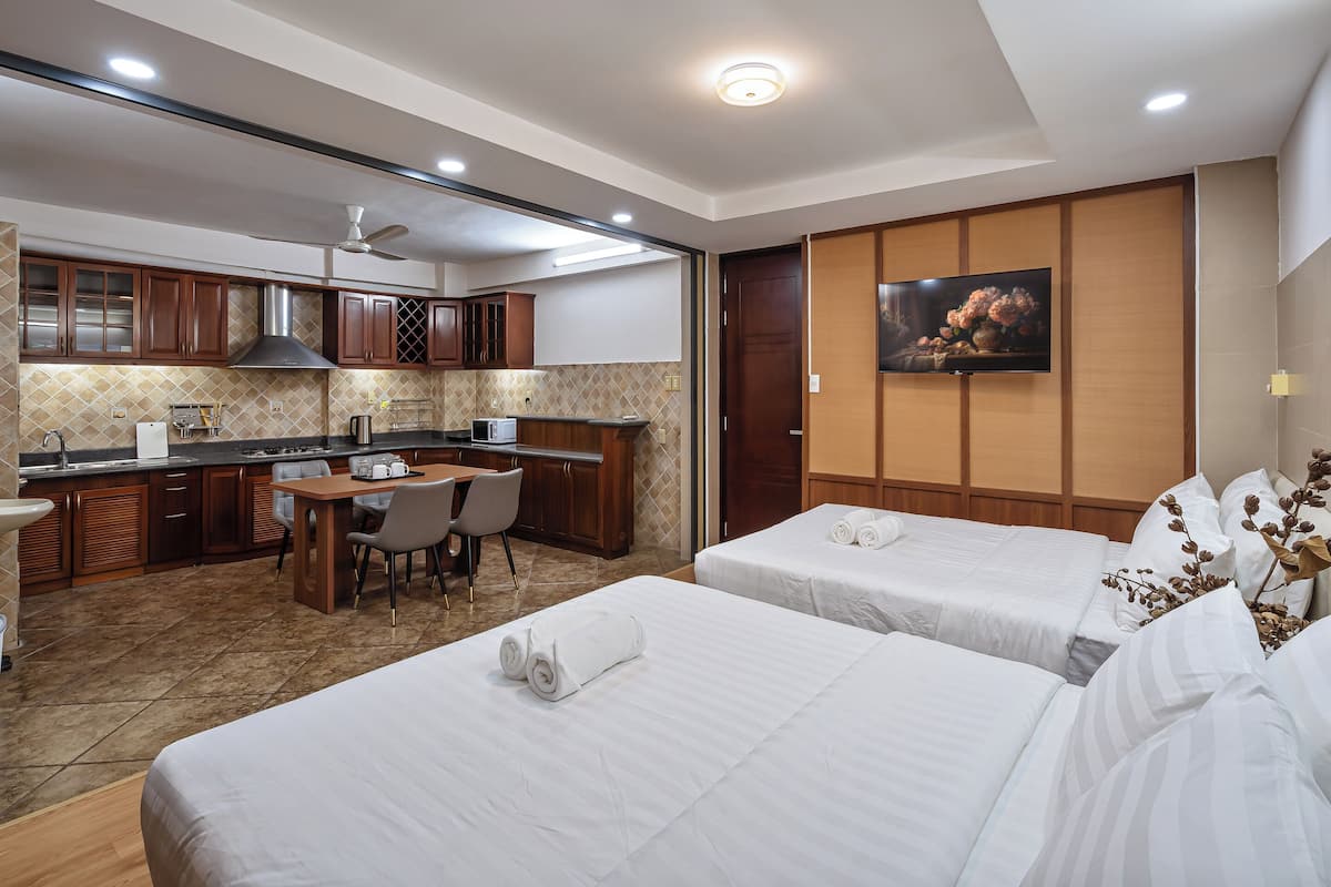 Hotelkamer met twee bedden, een kitchenette, een eethoek en een televisie.